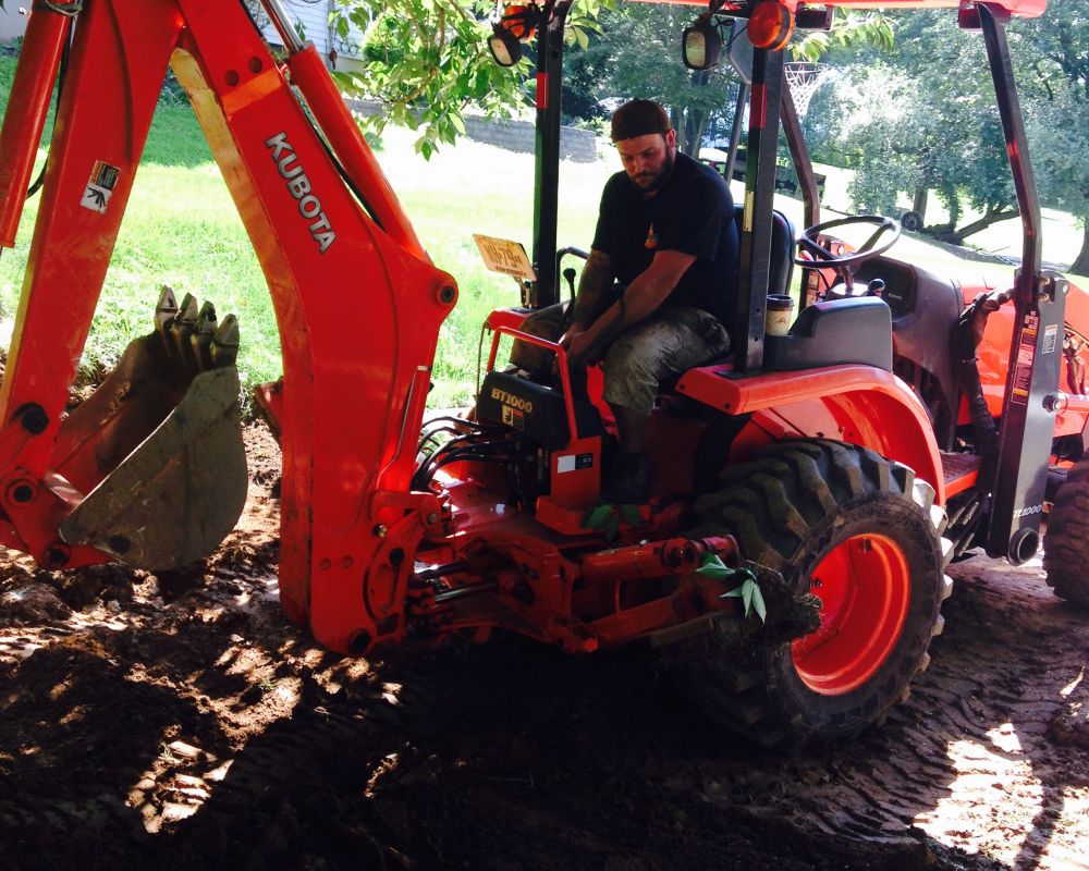 Backhoe removing soil during driveway installation