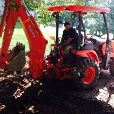 Backhoe removing soil during driveway installation