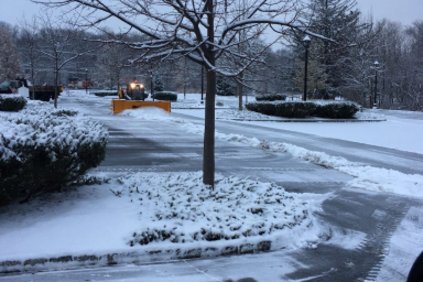 Loader with a snow pusher clearing a commercial office park parking lot at dawn in NJ
