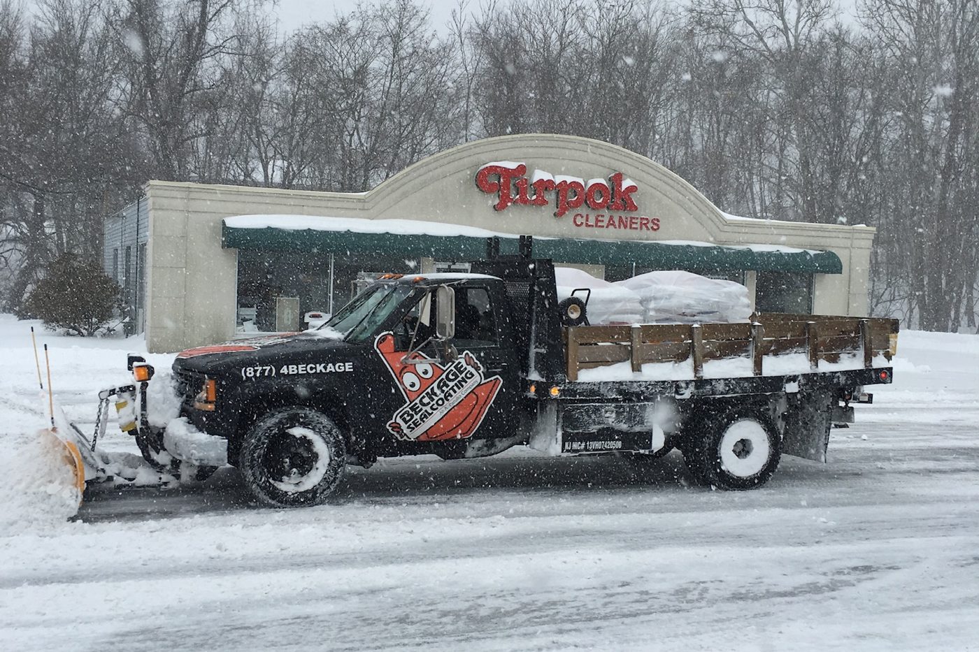 Beckage Sealcoating plow truck clearing a commercial parking lot during a snowstorm in Hunterdon County NJ